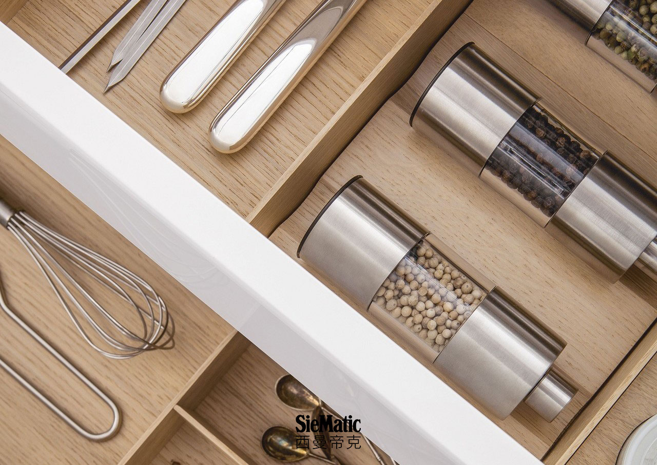 Spice mills and porcelain jars inside a SieMatic drawer with wooden accessories