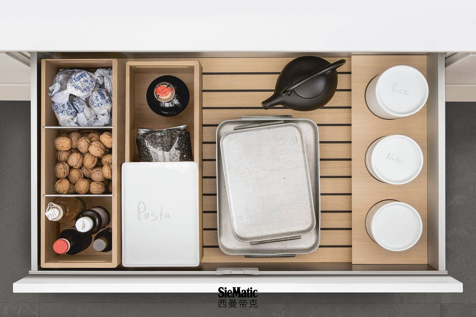 Porcelain containers, bottles and other supplies on SieMatic GripDeck with wooden kitchen accessories